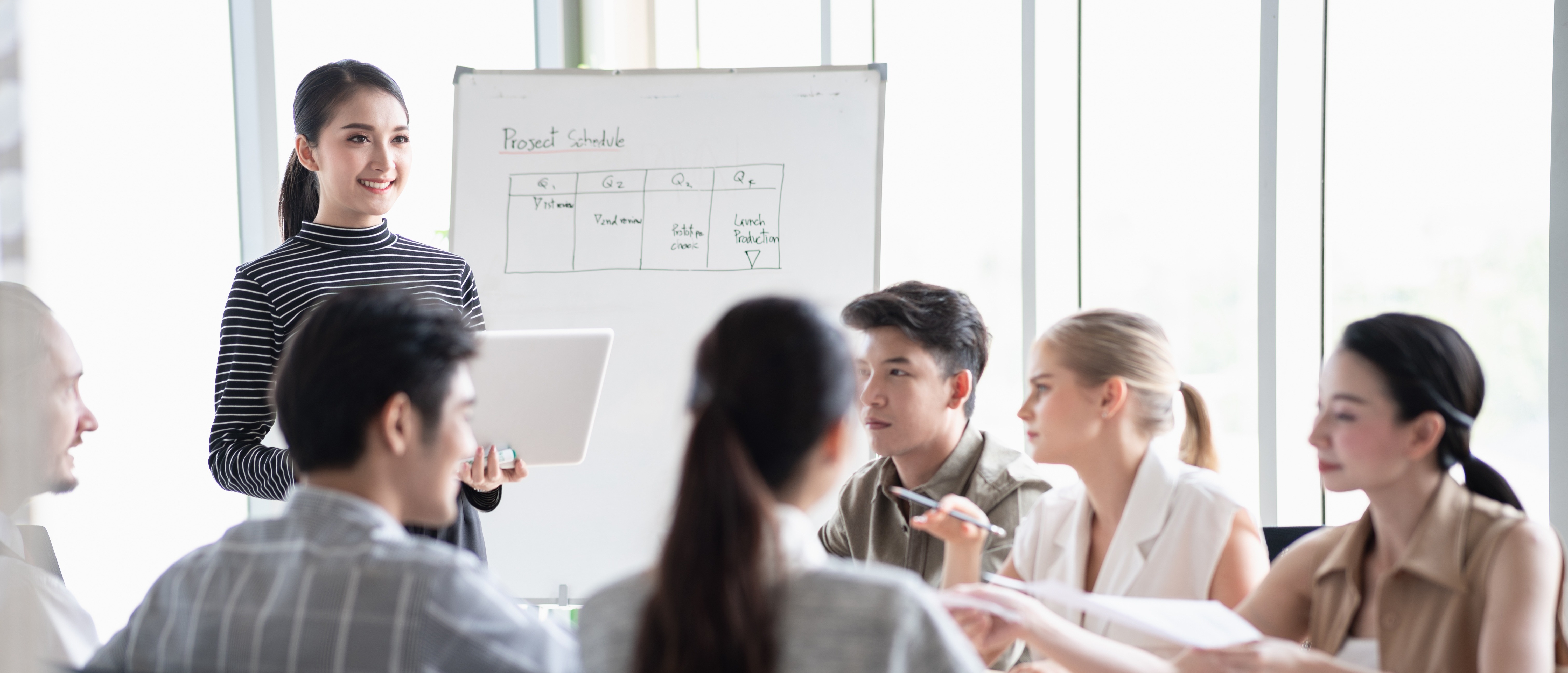 A female presenting in front of a white board to a group